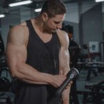 Een persoon die een massagegun gebruikt op zijn kuiten voor spierherstel na het sporten.